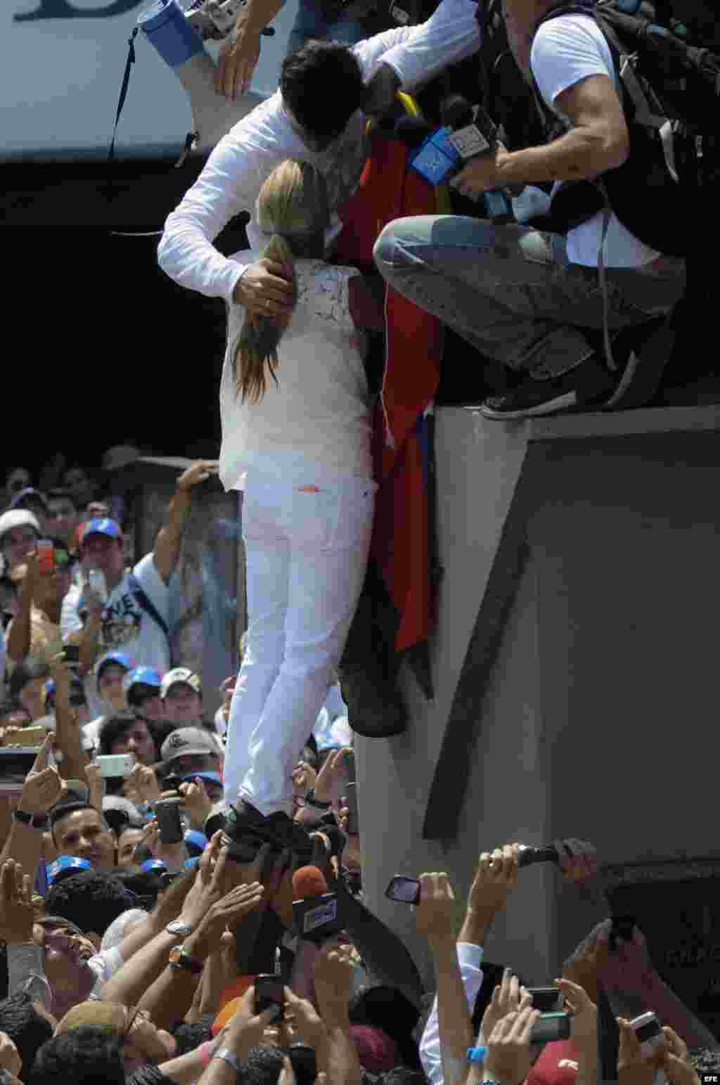 El dirigente opositor venezolano Leopoldo López (i-arriba)da un abrazo a su espoza Lilian Tintori (i) antes de ofrecer un discurso a sus seguidores y entregarse a miembros de la Guardia Nacional (GNB,